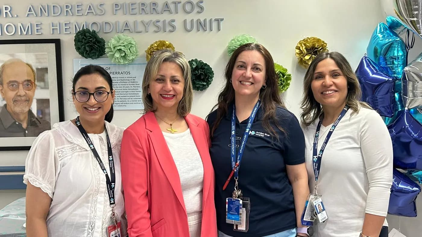 Jasraj with three colleagues in front of the home hemodialysis unit sign