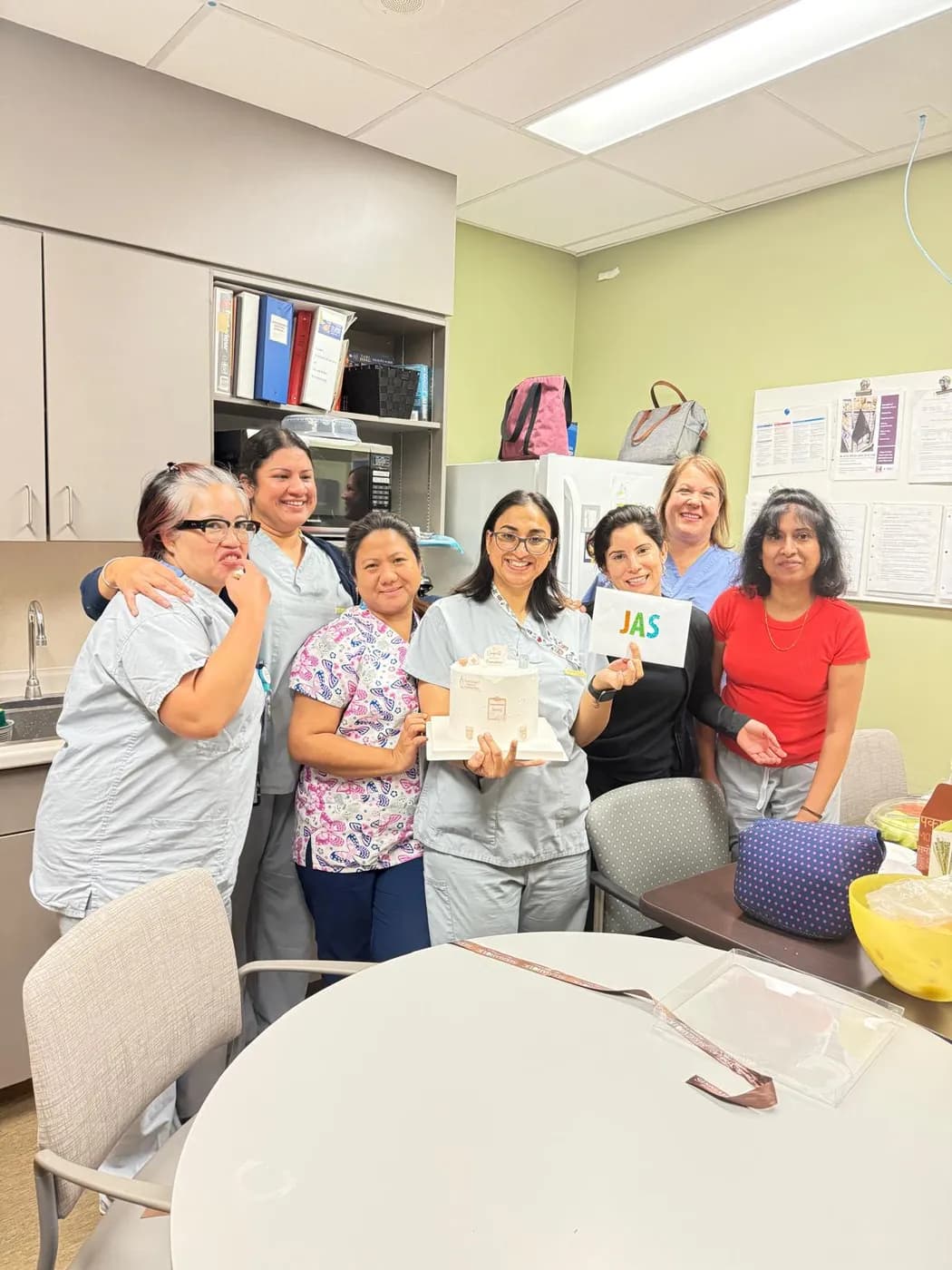 Jasraj holding a celebration cake surrounded by her nursing team